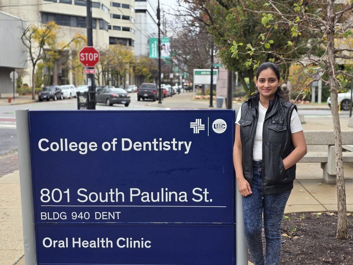 Shahana standing beside the College of Dentistry sign at 801 South Paulina Street
