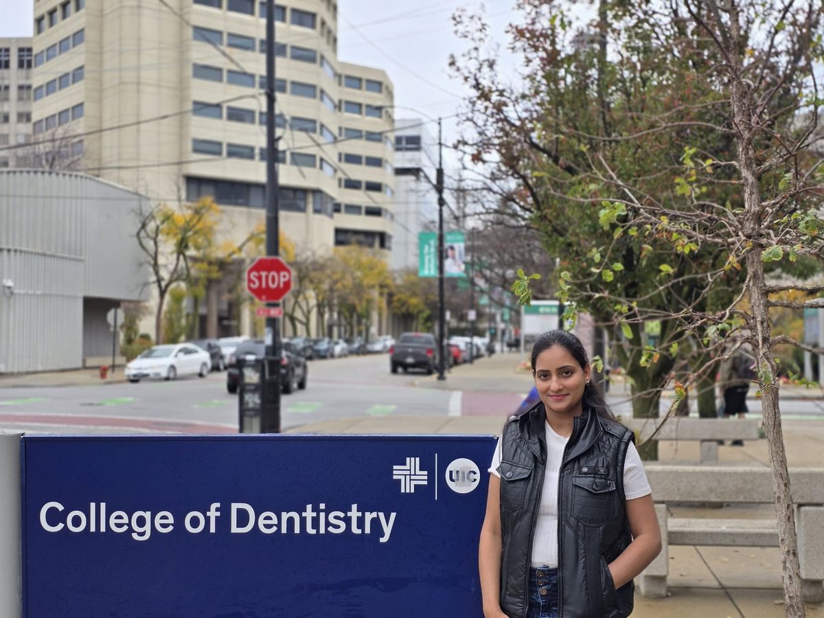Shahana standing next to the College of Dentistry sign on the University of Illinois Chicago campus