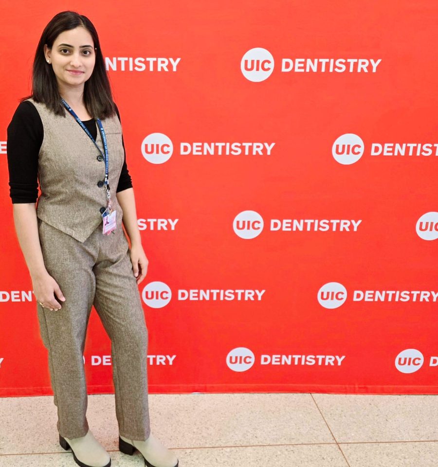 Shahana Putta Jegadeshan standing in front of a red UIC Dentistry backdrop